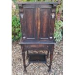 AN EDWARDIAN OAK CABINET ON STAND The two panelled cupboards above three drawers and a lower
