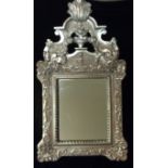 A 20TH CENTURY CARVED WOODEN MIRROR Having a fleur de lis finial above a floral basket,