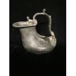 A ROMAN PATINATED COPPER WINE JUG The scroll work handle cast with leaves and a seated figure, the