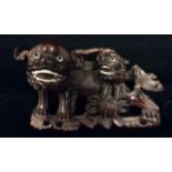 A 19TH CENTURY ORIENTAL HARDWOOD FIGURAL CARVING OF FO DOGS At play, a large dog with finely