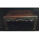 AN ANTIQUE CHINESE HARDWOOD LOW TABLE With a rectangular tip above a carved apron, raised on