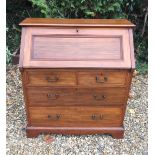 AN EDWARDIAN WALNUT WRITING BUREAU The fall front enclosing a fitted interior and tooled leather