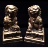 A PAIR OF 20TH CENTURY CAST BRASS TEMPLE DOGS OF FO One having a ball under foot, the other a