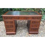 A VICTORIAN OAK TWIN PEDESTAL DESK Having a green tooled leather top over an arrangement of nine