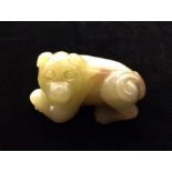 A CHINESE YELLOW JADE CARVING A recumbent dog with folding paws, with a scrolling tail and smiling