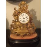 A GILT SPELTER MANTLE CLOCK Having enamelled dial with Roman numeral chapter ring, the scroll