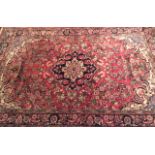 A PERSIAN MEDALLION WOOL RUG Having a central medallion with a stylized flower design and floral