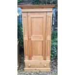 A CONTEMPORARY PINE WARDROBE With an ogee pediment over a single panelled door and drawer, raised on