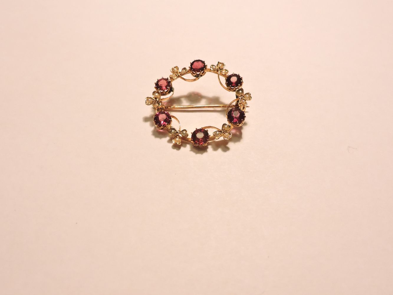 A garnet and split pearl circular brooch, indistinctly marked 15ct