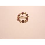 A garnet and split pearl circular brooch, indistinctly marked 15ct