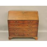 A Georgian mahogany bureau, the fall front enclosing pigeon holes over drawers and ogee bracket