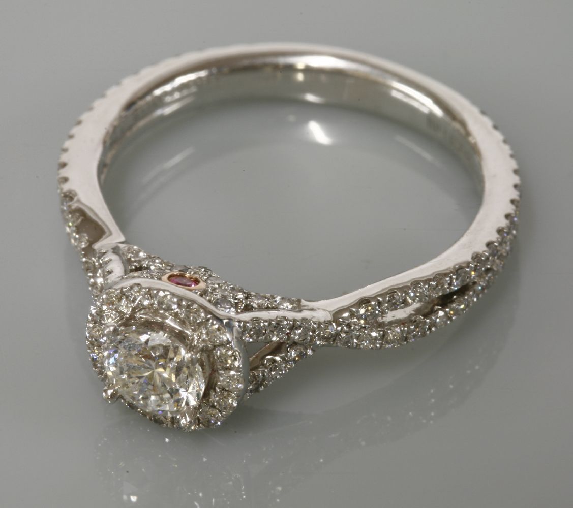 A white gold diamond set halo cluster ring, by Michael Hill, with crossover diamond set shoulders