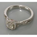 A white gold diamond set halo cluster ring, by Michael Hill, with crossover diamond set shoulders