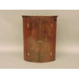 A George III bow front hanging corner cupboard, 70cm wide