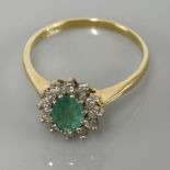 An 19ct gold emerald and diamond oval cluster ring