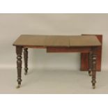 A small early Victorian mahogany supper table, with two leaves, on turned legs and brass castors,