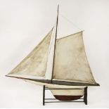 A Victorian pond yacht, with shallow hull and canvas sails, on stand, 131cm long, 136cm high