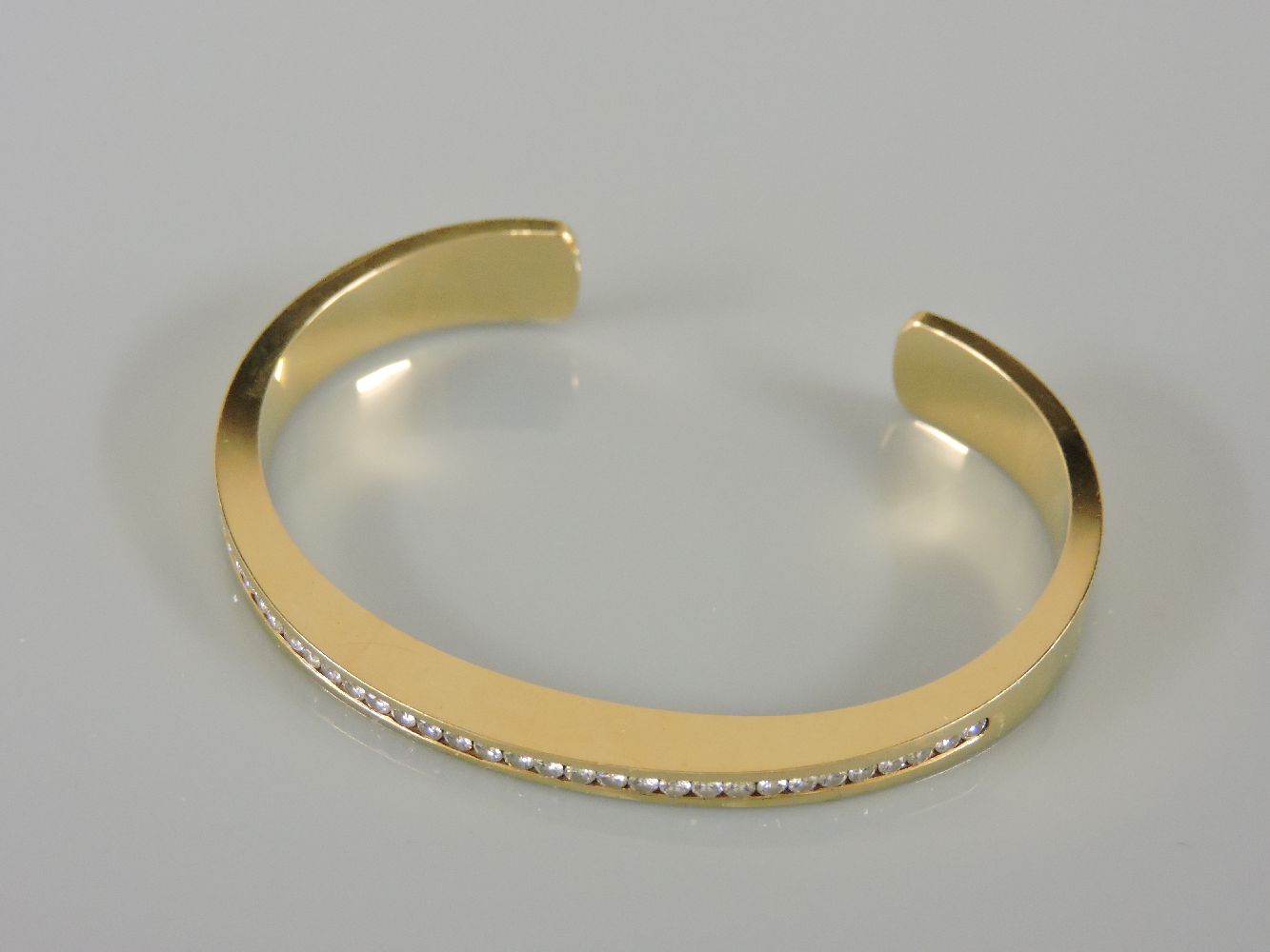An 18ct gold diamond set torque bangle, with a row of channel set brilliant cut diamonds, believed