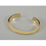 An 18ct gold diamond set torque bangle, with a row of channel set brilliant cut diamonds, believed