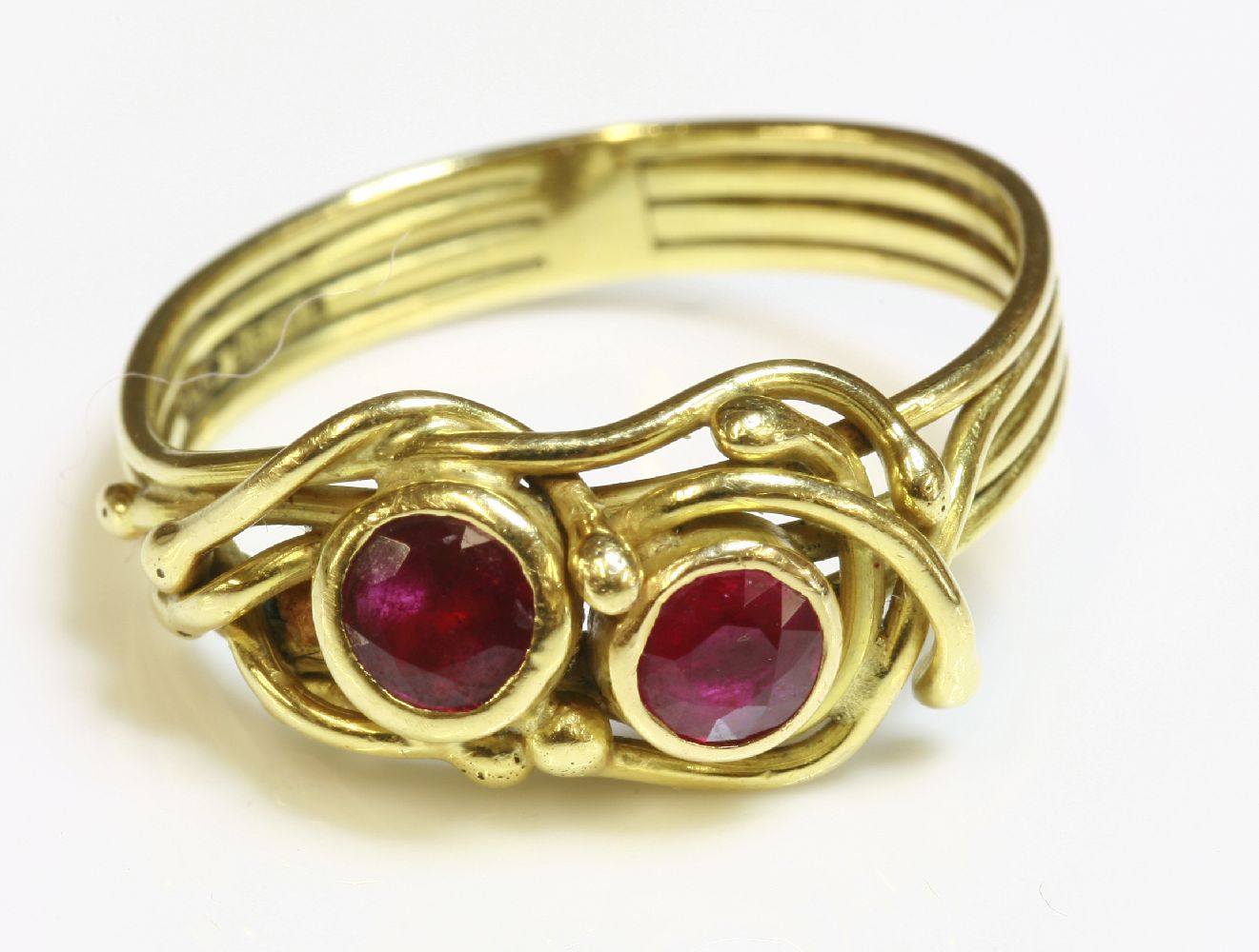 An 18ct gold two stone ruby ring by Susan Wright, with two circular mixed cut rubies rub set in