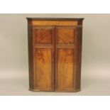 A 19th century mahogany hanging corner cupboard, with twin panelled doors, shaped shelves and