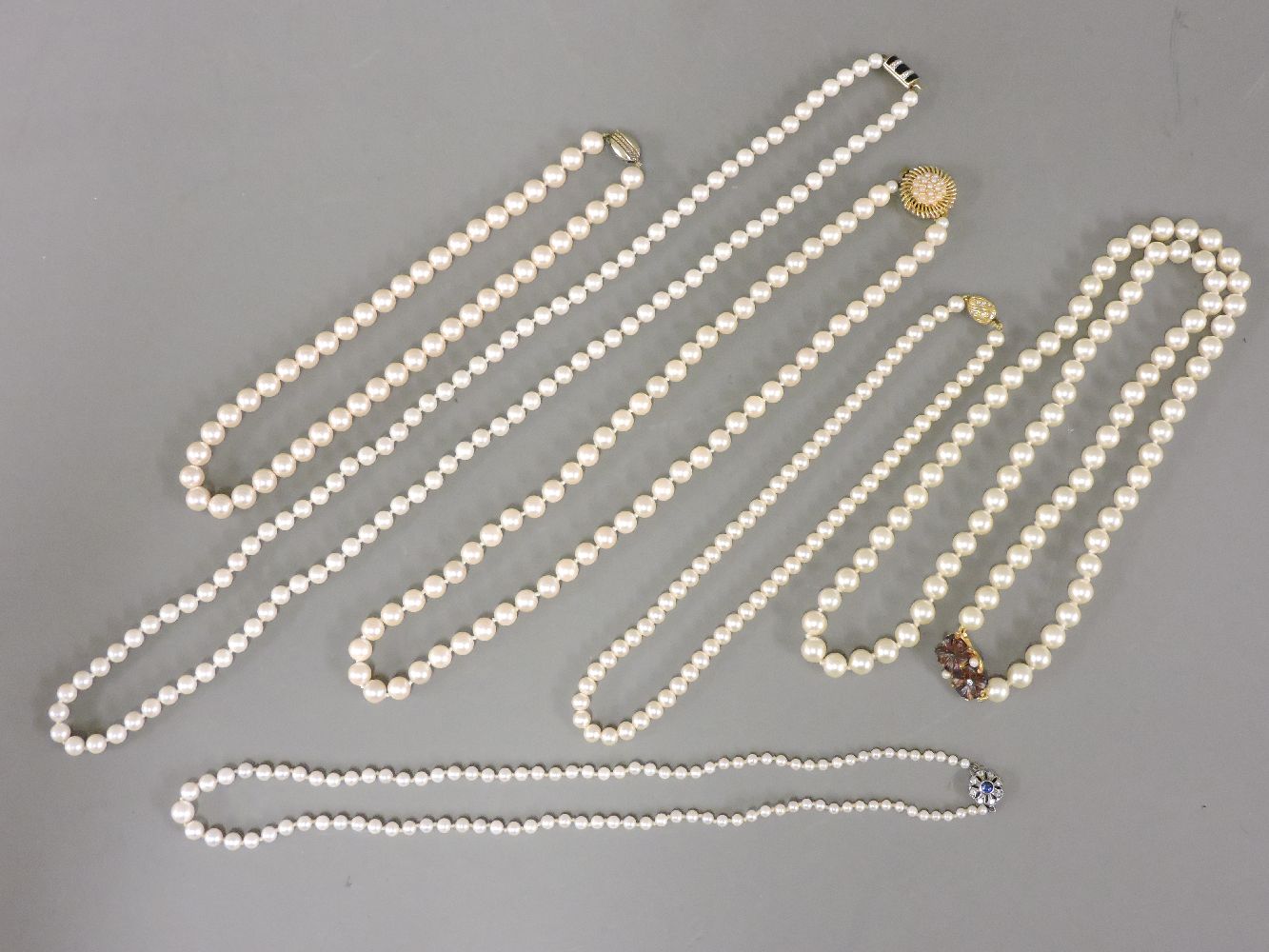 A single row graduated cultured pearl necklace, with a paste set clasp, together with five cased