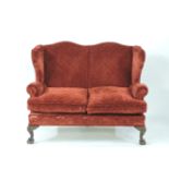 A red upholstered wing back settee, on cabriole legs, 132cm wide