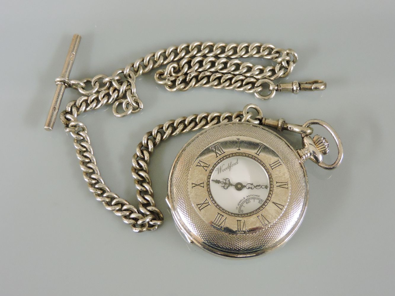 A sterling silver Woodford half hunter pocket watch, with engine turned decoration, suspended on a