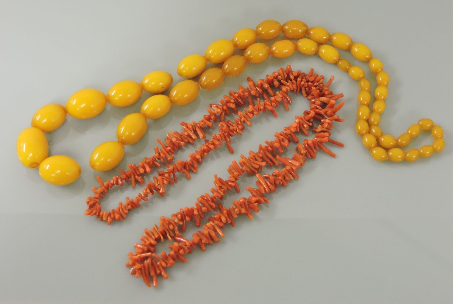 A graduated olive shaped bakelite bead necklace, 60.8g, and a graduated twig coral necklace