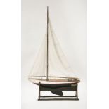 An early 20th century pond yacht, with canvas sails, on stand, 99cm long, 162cm high