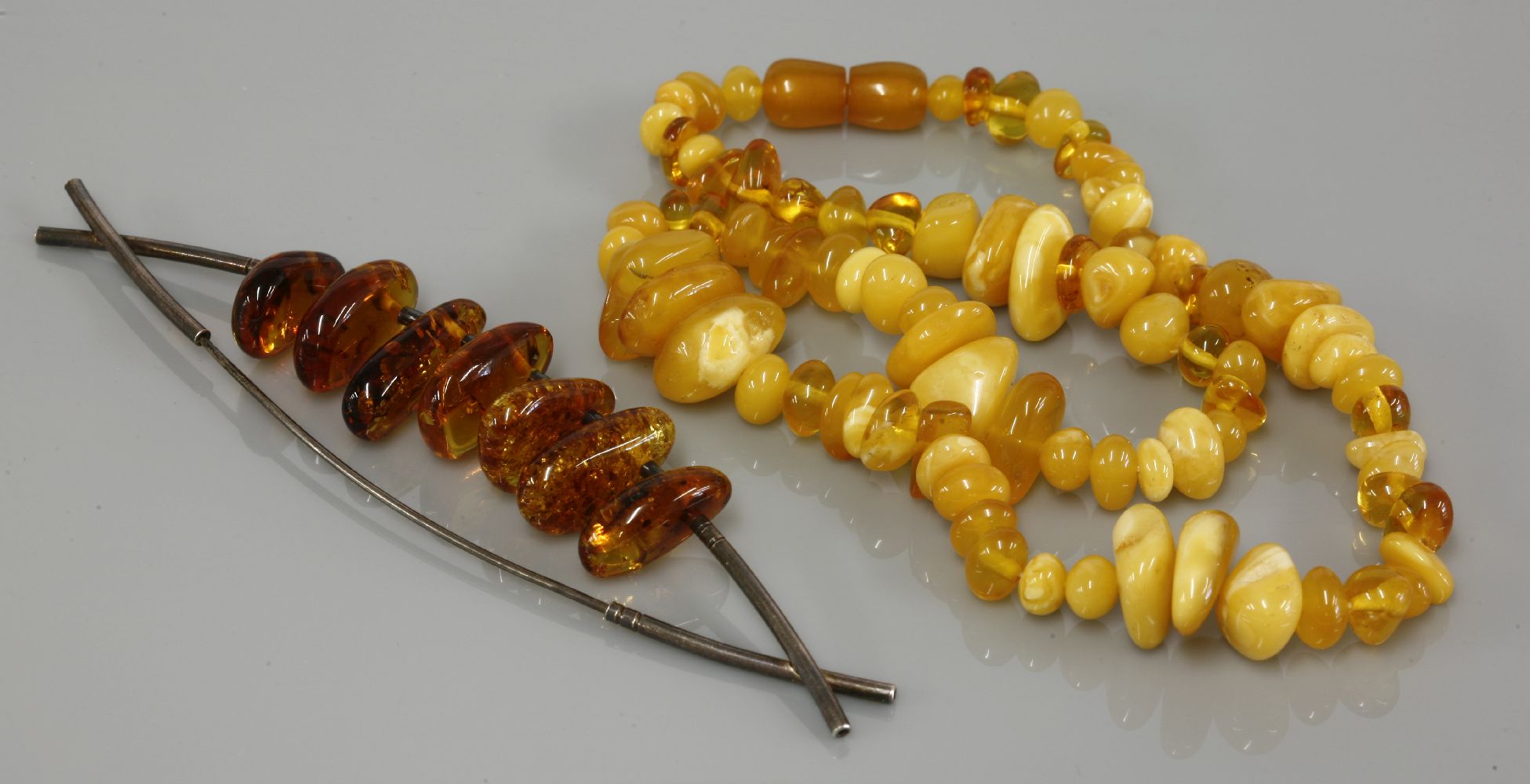 A single row graduated free form amber bead necklace, of varying shades, together with a