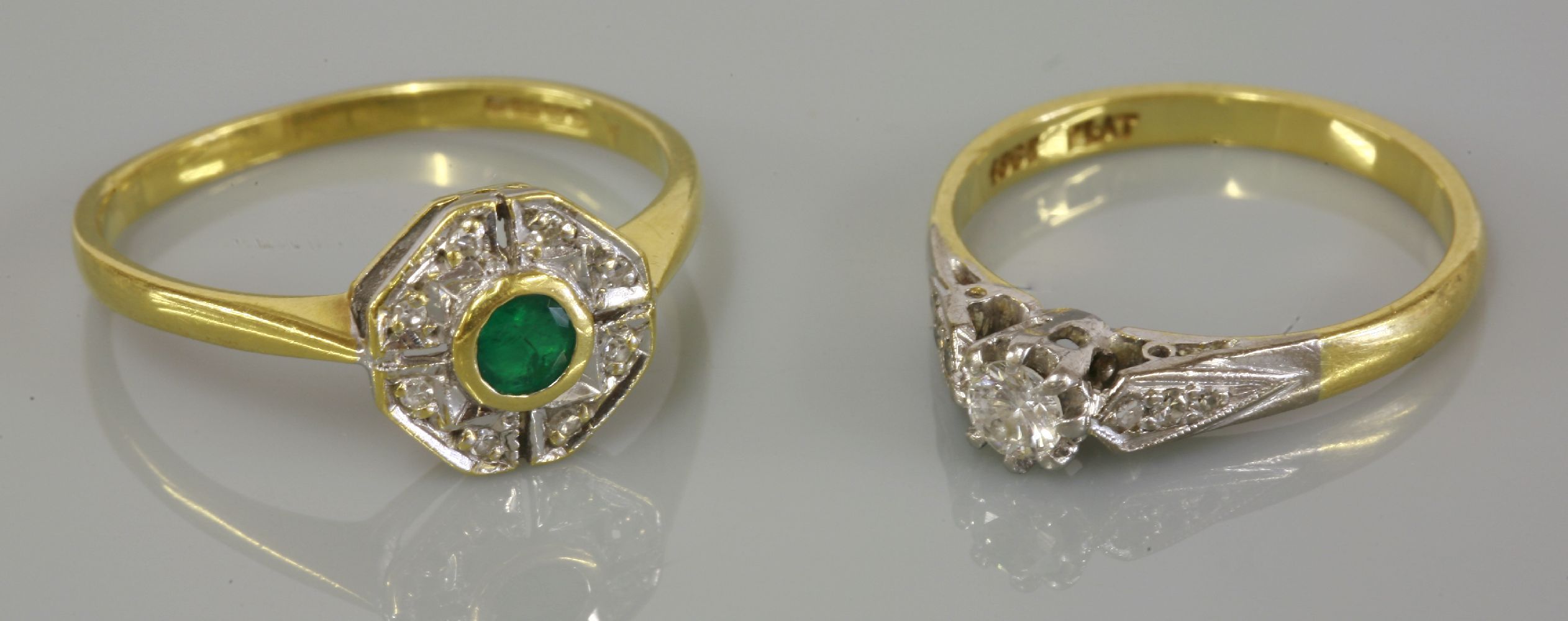 A single stone diamond ring, marked 18ct plat, and an 18ct gold emerald and diamond cluster ring