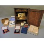 An oak smoker's cabinet, 34cm high, containing pre decimal coins, two boxed Victoria Diamond Jubilee