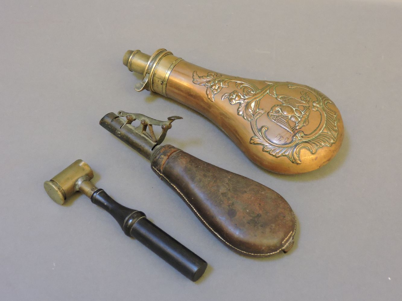 A copper powder flask, with American eagle decoration, a leather shot flask, and a powder measure