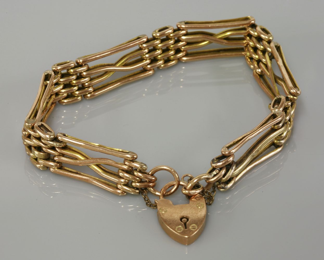 An Edwardian gold four row gate bracelet, marked 9ct, 12.76g