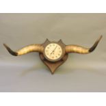 A horn clock, with 6½in dial, mounted on an oak shield, 84cm wide