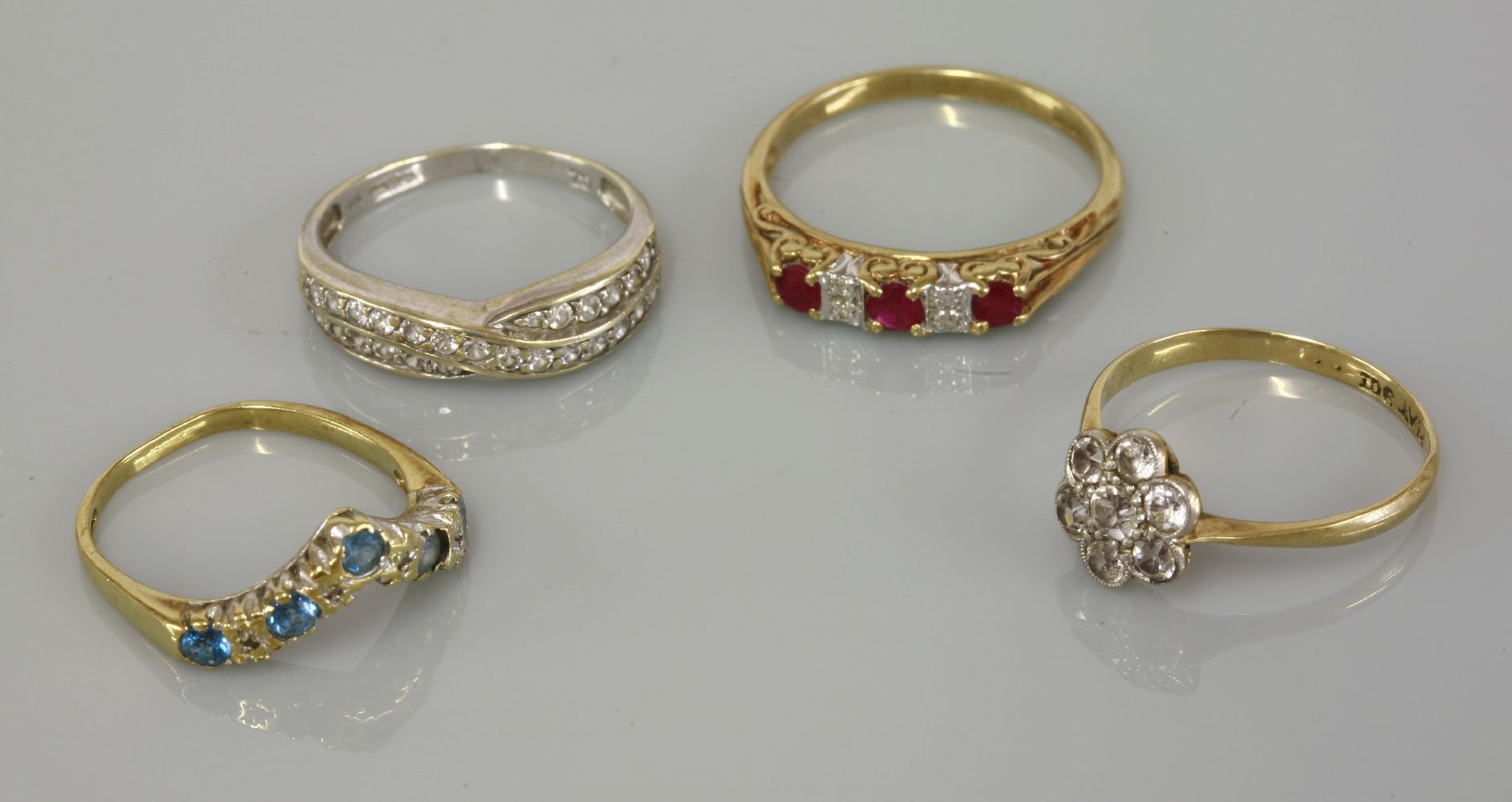 A 9ct gold three stone ruby ring, with pairs of diamond set points, a 9ct gold blue topaz and