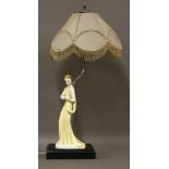 An Art Deco pottery table lamp,modelled as a lady in a yellow dress, on an ebonised plinth, with a