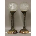 A pair of Art Deco style bronze table lamps,with frosted glass globes moulded with butterflies and