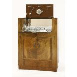 An Art Deco burr walnut cocktail cabinet,labelled 'Hospitality Cabinet' the hinged top, opening to