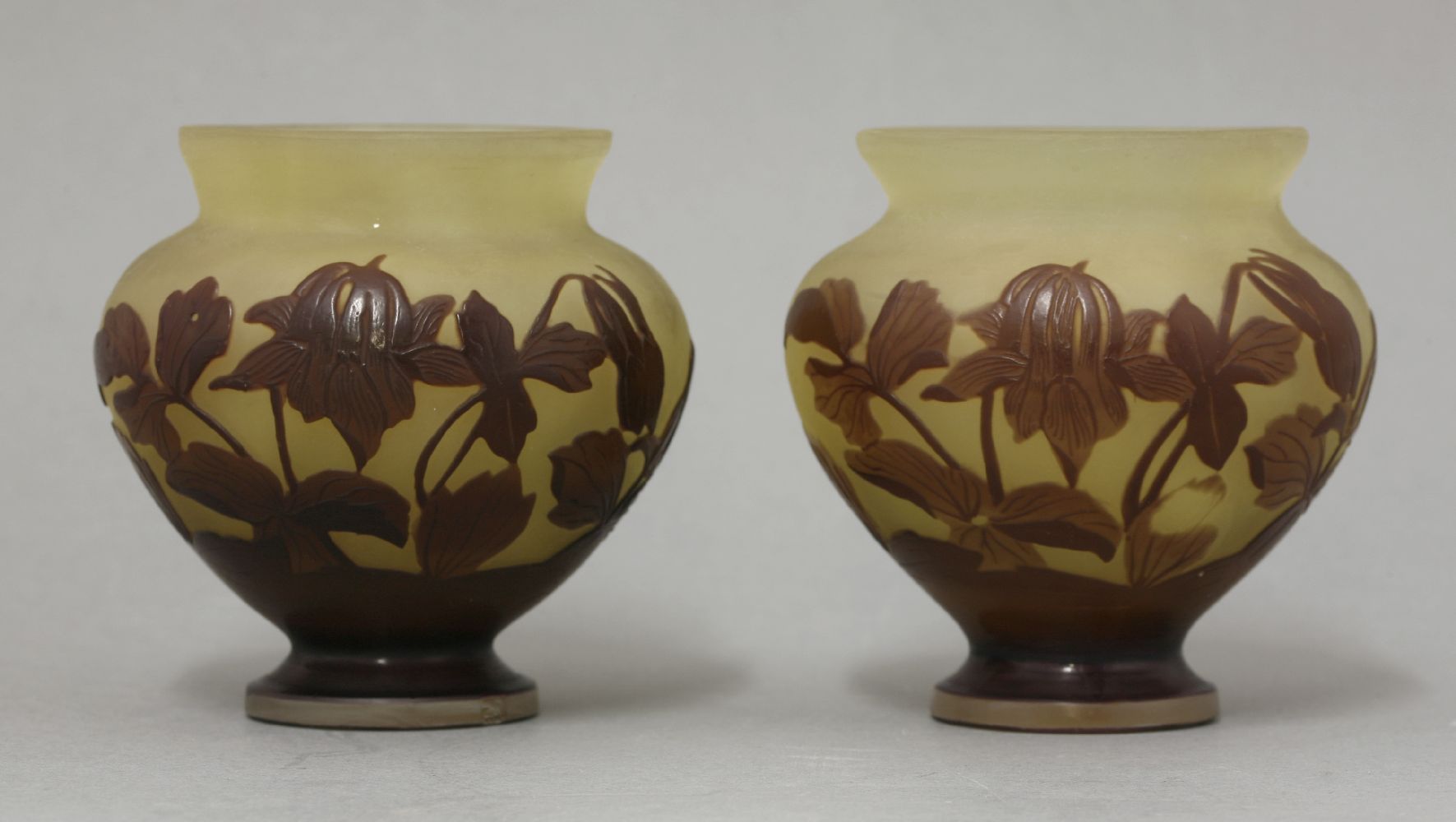 A pair of Gallé cameo glass vases,in amber and polished purple glass in the form of flowers,