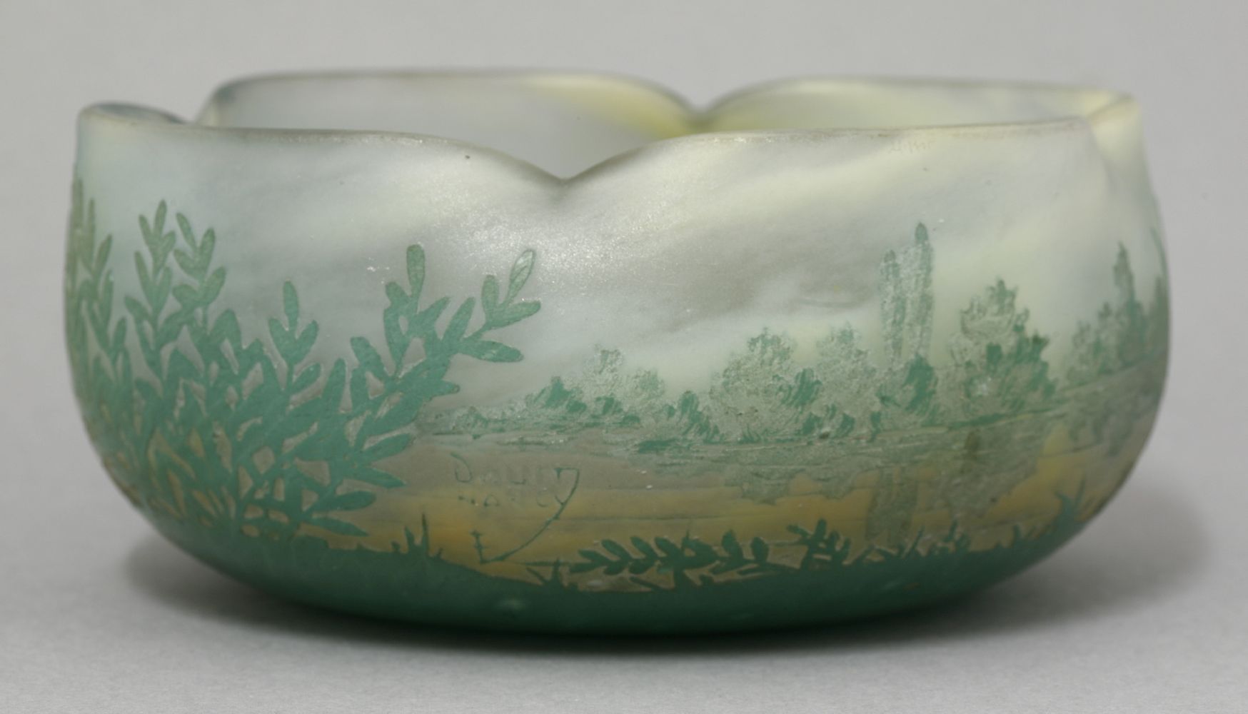 A Daum Nancy etched bowl, quatrelobed form and decorated with a river landscape with bushes and