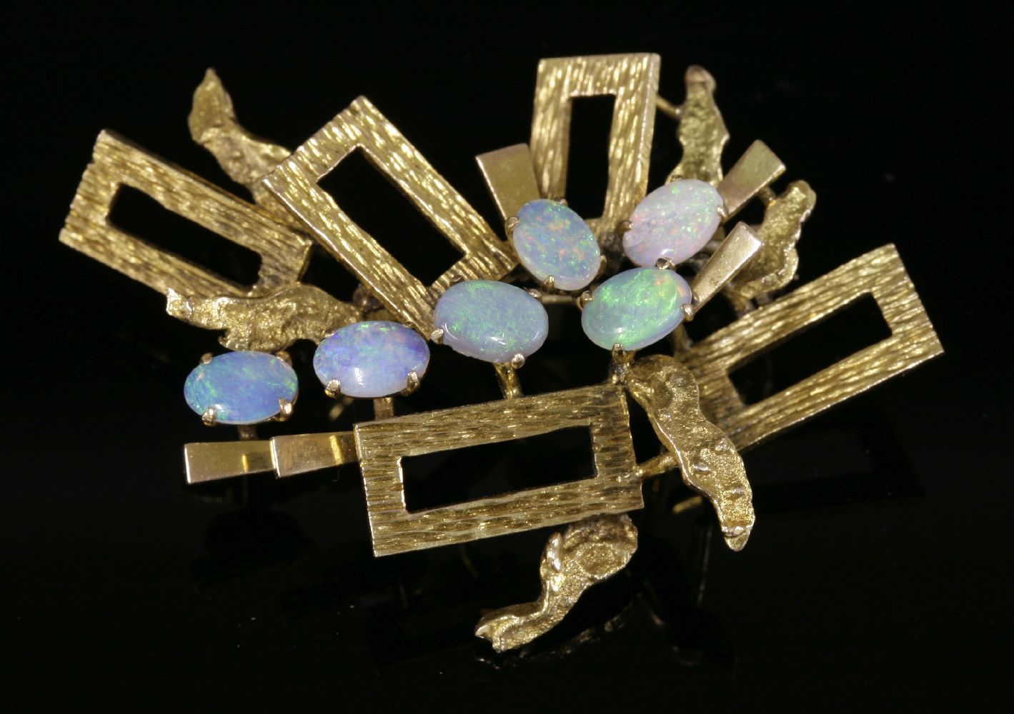 A Continental gold opal brooch, c.1970,with radiating rectangular frames, each frame with bark