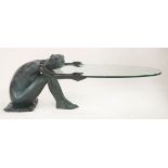 A contemporary coffee table,modelled as a female nude holding an oval glass top,150cm long39cm