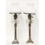 A pair of Elkington & Co. silver-plated candlestick oil lamps,with cut glass reservoirs, raised on
