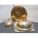 Two dish covers, one engraved with a crest, a large silver plated tray, and a brass tray