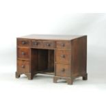 A country made oak architect's desk, with sloping top and a variety of drawers around a central