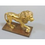A gilt lion, stamping with its foot on a ball, with a chased mane