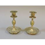 A pair of brass candlesticks, with pierced bases, with oval portrait medallions, 14cm