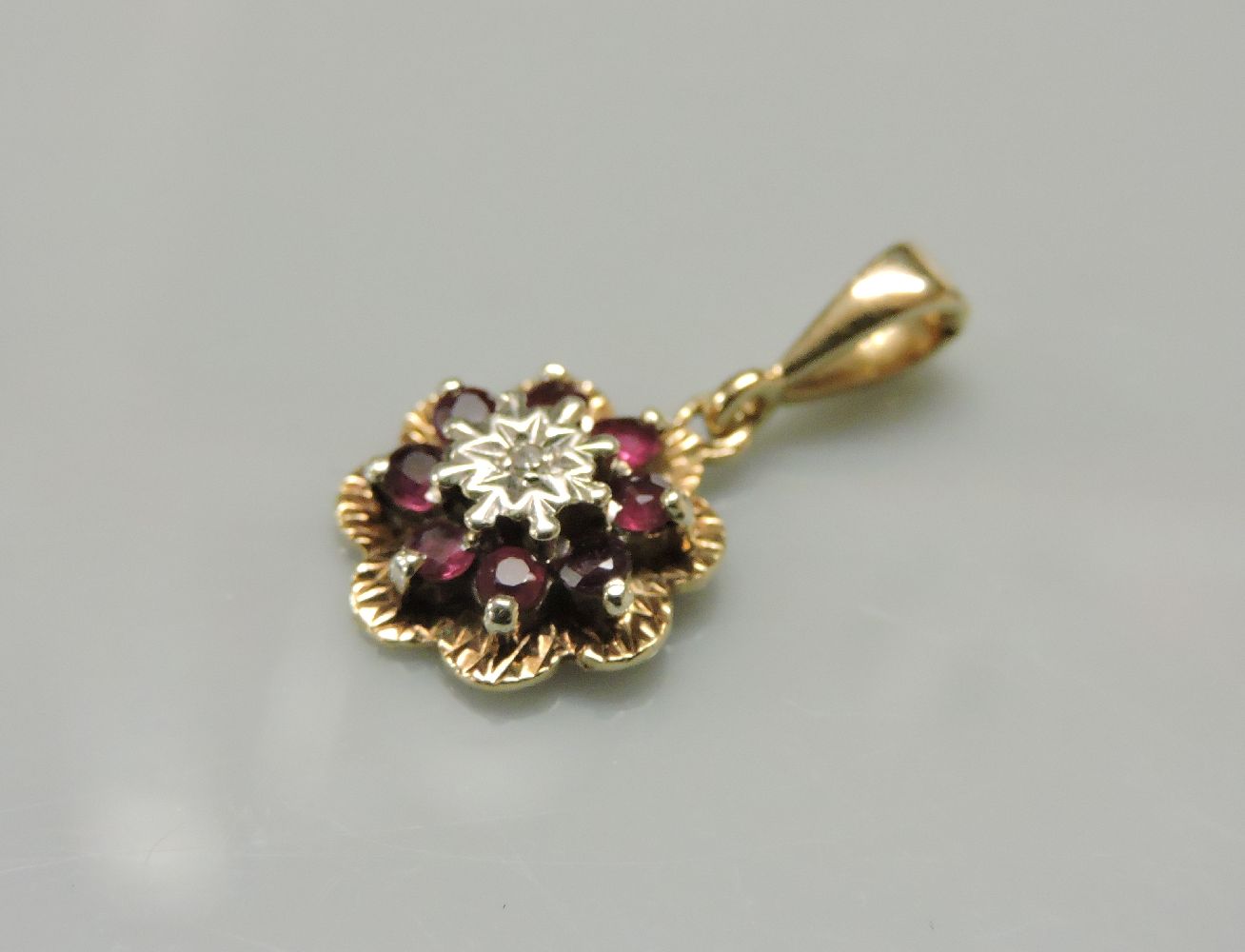 A 9ct gold illusion set diamond and ruby cluster pendant